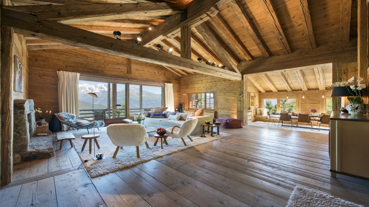 Chalet Bibi, Verbier. Spacious open-plan living area with a stone fireplace surrounded by retro chairs