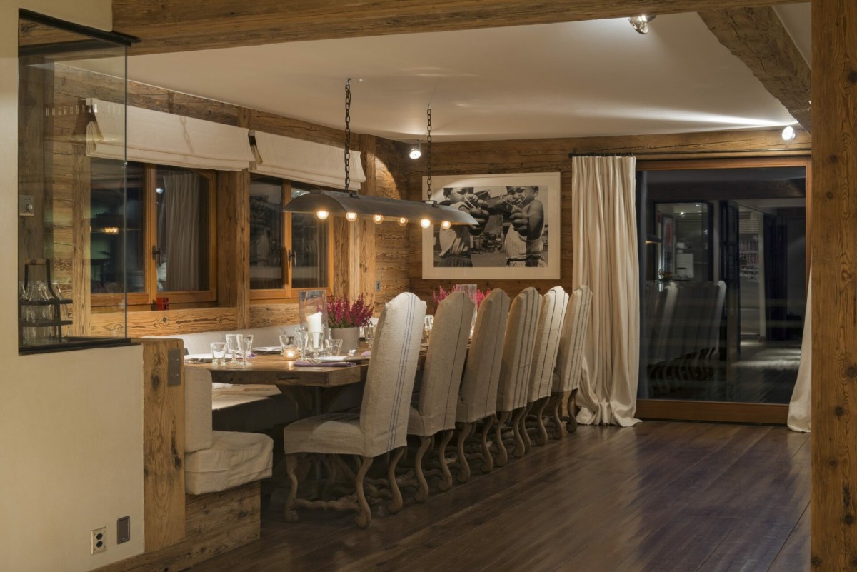 Chalet 1936, Verbier – at the far end of the open-plan living space, a 14-seater dining table set under contemporary lighting is the perfect setting for long mealtimes