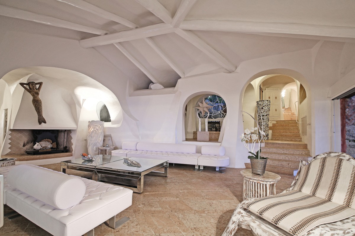 Villa Anna's living area seamlessly blends modern interiors with Sardinian charm, boasting high ceilings with white wooden beams.