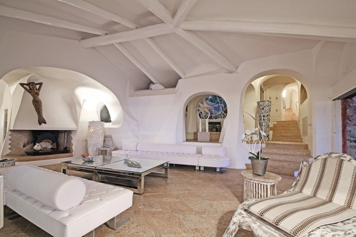 Villa Anna's living area seamlessly blends modern interiors with Sardinian charm, boasting high ceilings with white wooden beams. Villa Anna's living area seamlessly blends modern interiors with Sardinian charm, boasting high ceilings with white wooden beams.